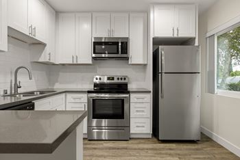 A modern kitchen with stainless steel appliances and white cabinets.at Brookside Terrace Apartments, California, 91316